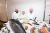 3 people standing next to a fresh fish counter display 